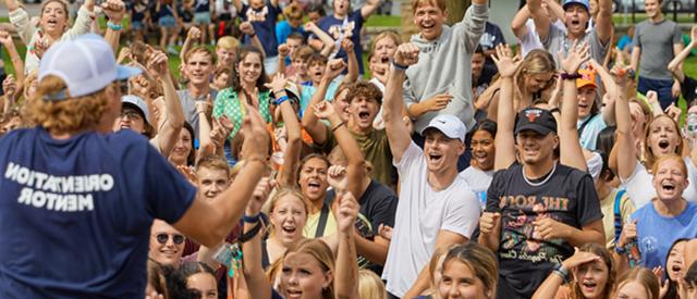 Crowd of students raising there hands with questions.